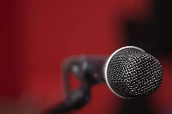 Closeup black vocal microphone mounted on mic stand, blurry red dark bcakground — Stock Photo, Image