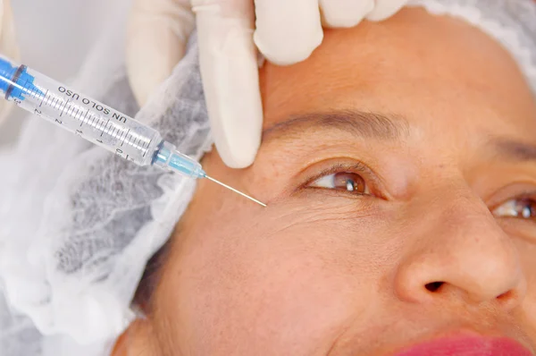 Primeros planos de las mujeres se enfrentan a recibir inyecciones antiarrugas con jeringa, concepto de cirugía estética, como se ve desde arriba —  Fotos de Stock