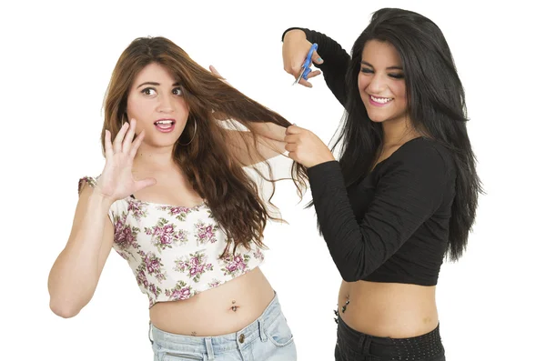 Beautiful young girl trying to cut her worried friends hair with scissors — Stock Photo, Image