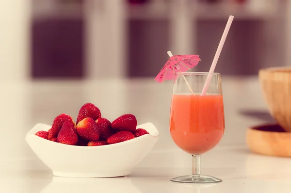 Läckra jordgubbar juice i ett glas och färska jordgubbar på skål — Stockfoto