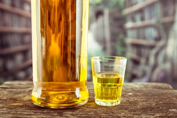 Láhve a sklo shot s žlutými liqour připomínající whiskey, rum, tequila, Duch — Stock fotografie