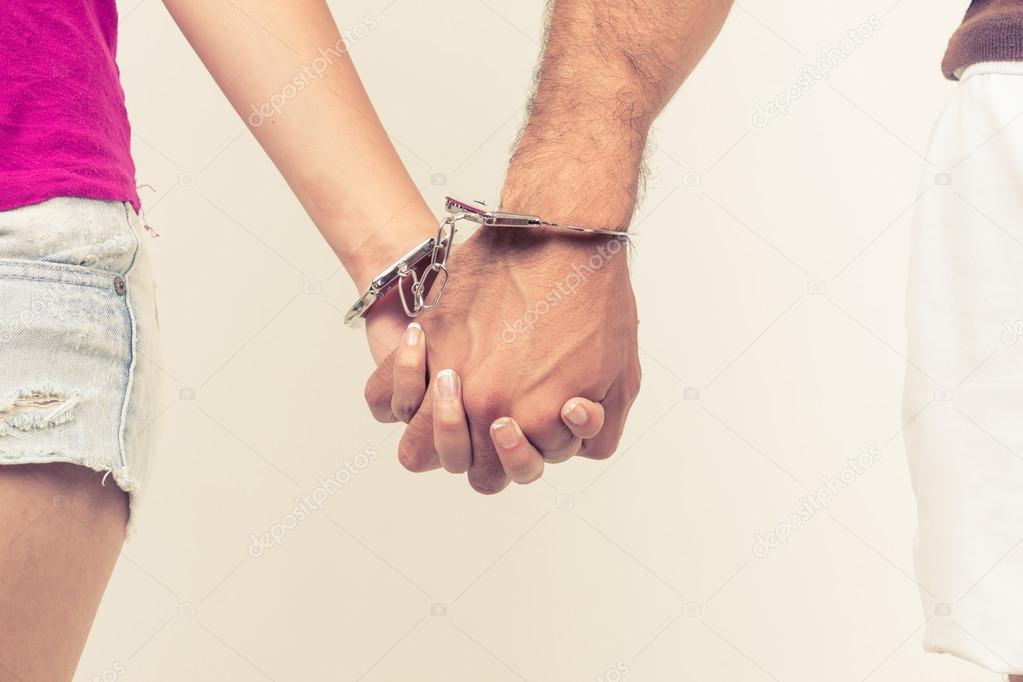 Man and womans hands handcuffed together