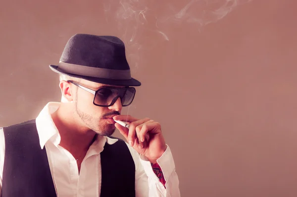 Young handsome stylish male model smoking a cigarette