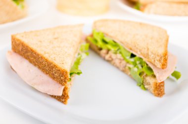 Beyaz bir plaka üzerinde jambon ve salata sandviç