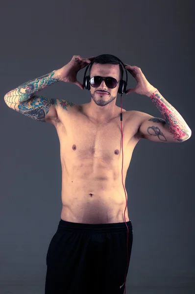 Guapo joven sin camisa hombre tatuado usando auriculares — Foto de Stock