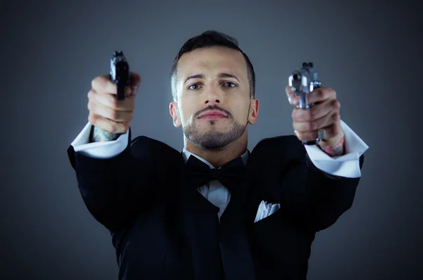 Sexy man in een smoking wijzen twee kanonnen — Stockfoto