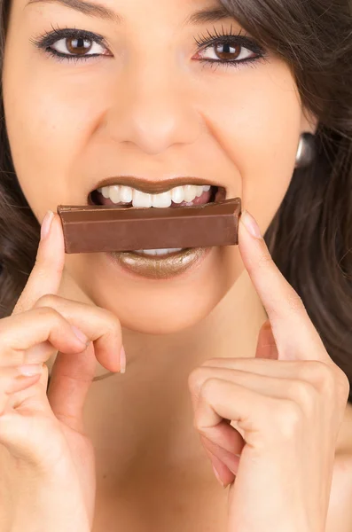 Beautiful young brunette girl eating chocolate — Stock Photo, Image