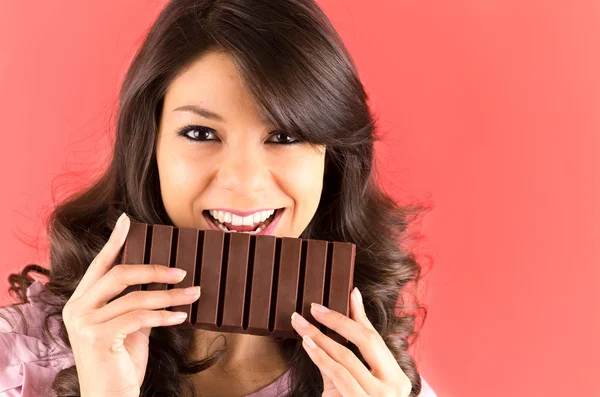 Beautiful young brunette girl eating chocolate — Stock Photo, Image