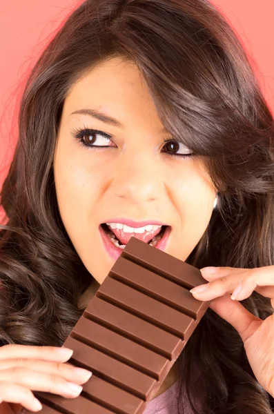 Beautiful young brunette girl eating chocolate — Stock Photo, Image