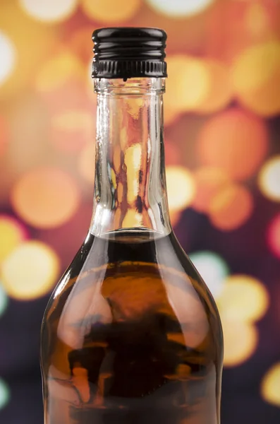 Bottle of rum whiskey over defocused lights background — Stock Photo, Image