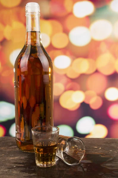 Glass of rum whiskey over defocused lights background — Stock Photo, Image