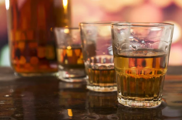 Shots of rum whiskey over defocused lights background — Stock Photo, Image