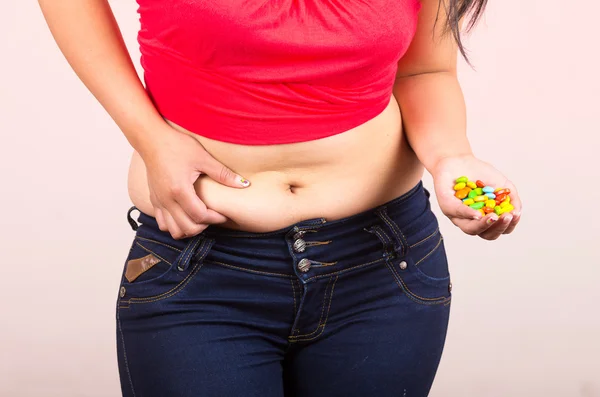 Young girl student holding candy sweets and grabbing her belly — Stock Photo, Image