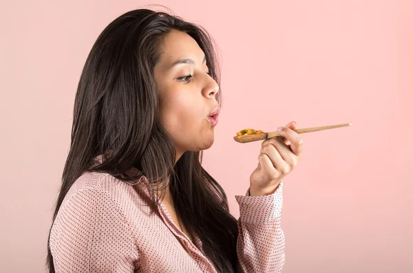 Young girl eating vegetables and rice from a wooden spoon — Stock Photo, Image