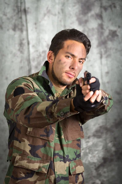 Солдат мілітарний латинський чоловік, який вказує на пістолет — стокове фото