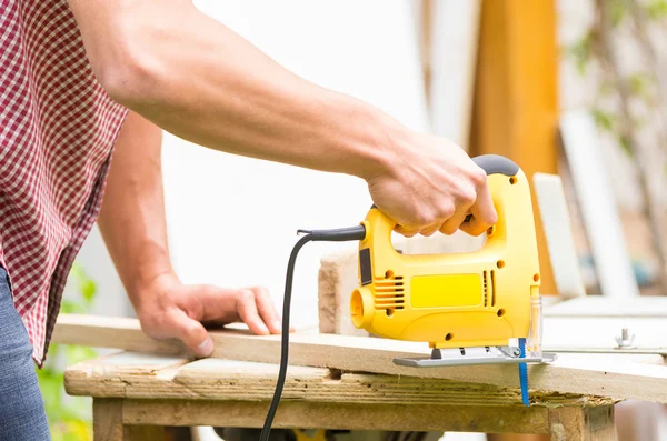 Jeune homme charpentier travaillant avec scie sauteuse électrique et bois — Photo