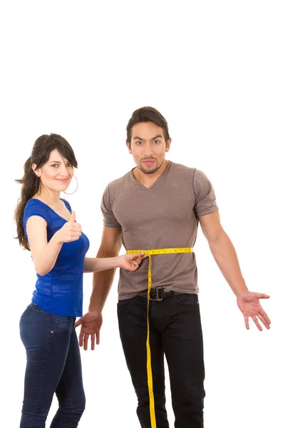 Beautiful girl holding measuing tape around handsome muscular man Stock Picture