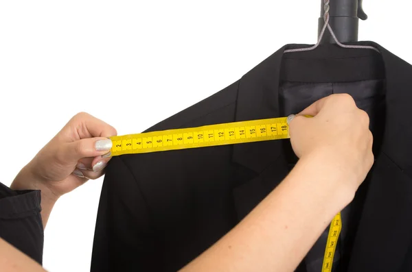 Tailors hand measuring a black suit — Stock Photo, Image