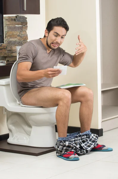 worried man sitting on the toilet running out of paper