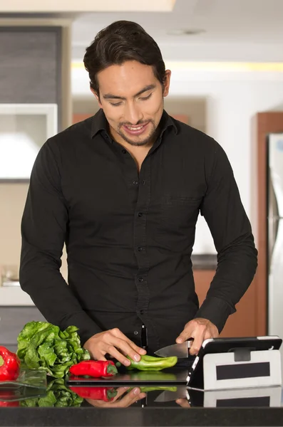 Beau jeune homme moderne cuisine recette saine et en utilisant tablette — Photo