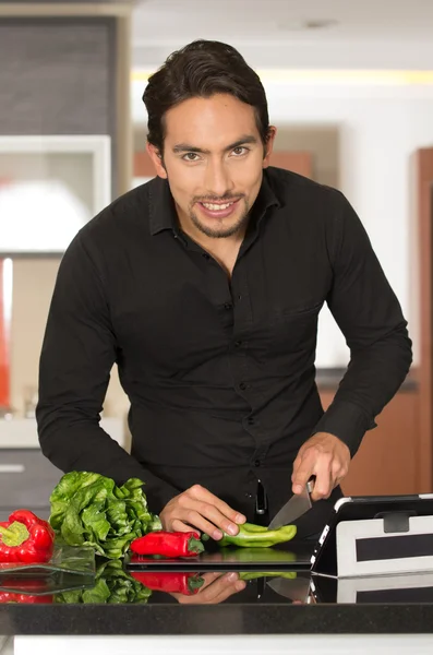 handsome young modern man cooking healthy recipe and using tablet