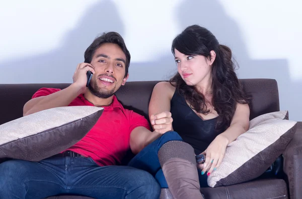 Noioso ragazza guardando la tv mentre fidanzato chatta al telefono — Foto Stock