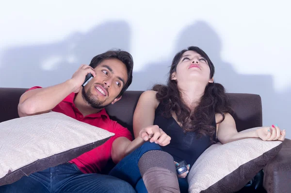 Entediado namorada assistindo tv enquanto namorado bate-papos no telefone — Fotografia de Stock