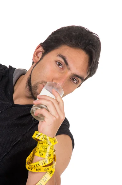 Handsome athletic young man wrapped around measuring tape drinking glass of milk — Stock Photo, Image