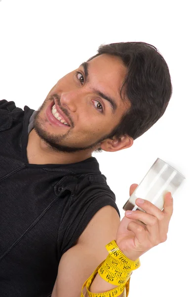 Guapo sonriente atlético joven envuelto alrededor de cinta métrica sosteniendo vaso de leche — Foto de Stock