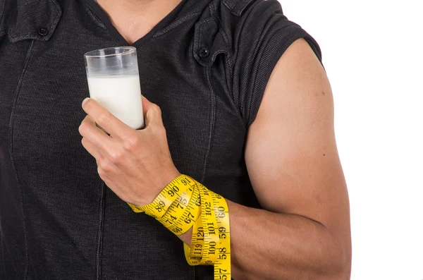 Athletische junge Männer Arm um Maßband gewickelt hält Glas Milch — Stockfoto