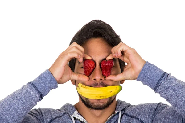 Nahaufnahme Porträt junger lustiger Mann, der Gesicht mit roten Erdbeeren und Banane bedeckt — Stockfoto