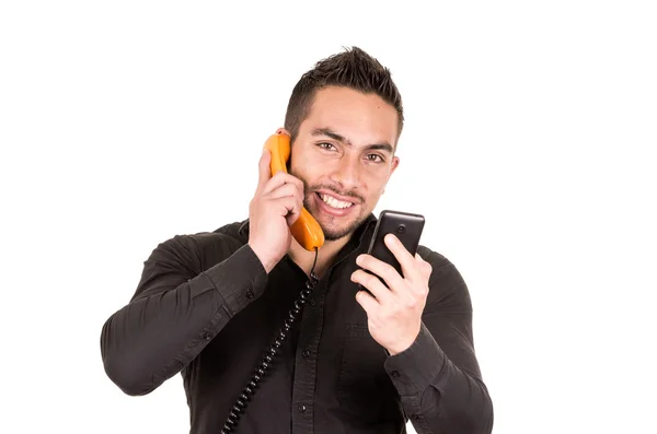 Närbild skott av stilig man med hjälp av sladd telefon och mobiltelefon — Stockfoto