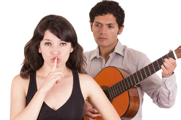 Schöne Mädchen gestikuliert Stille, während junger Mann ihr ein Ständchen mit der Gitarre bringt — Stockfoto