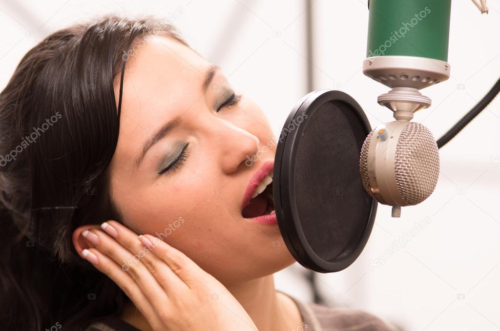 beautiful young girl singing in music studio