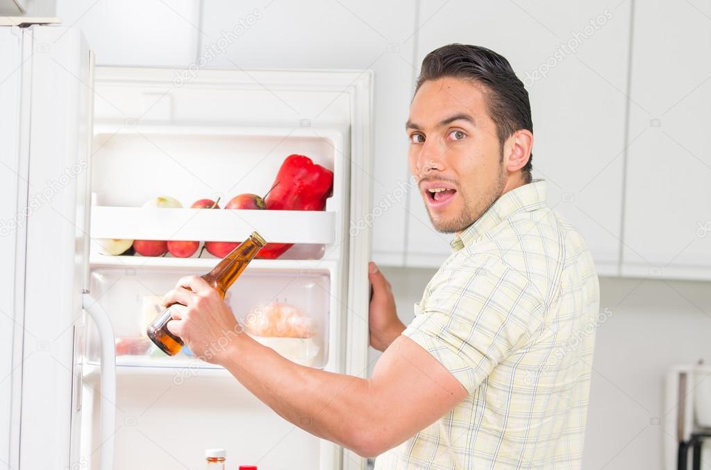 Young handsome man looking for food in the fridge Stock Photo by