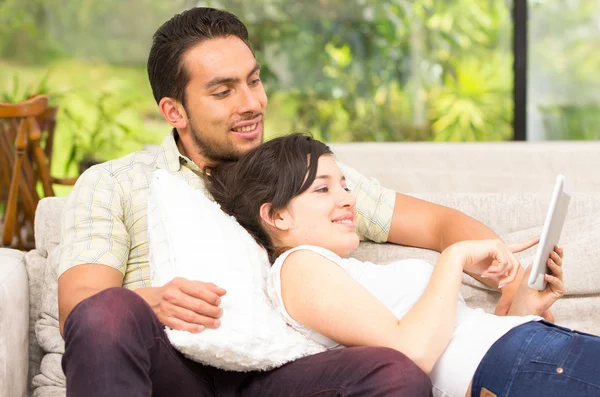 Jovem casal atraente relaxante no sofá usando tablet — Fotografia de Stock