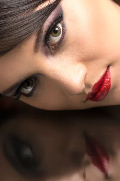 Mooie jonge vrouw het dragen van make-up en haar reflectie — Stockfoto