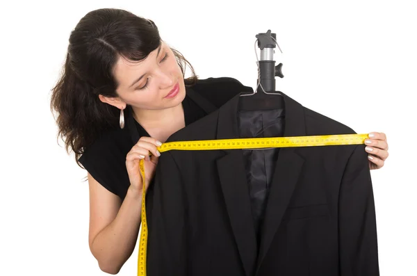 Beautiful young woman tailor measuring a black suit — Stock Photo, Image