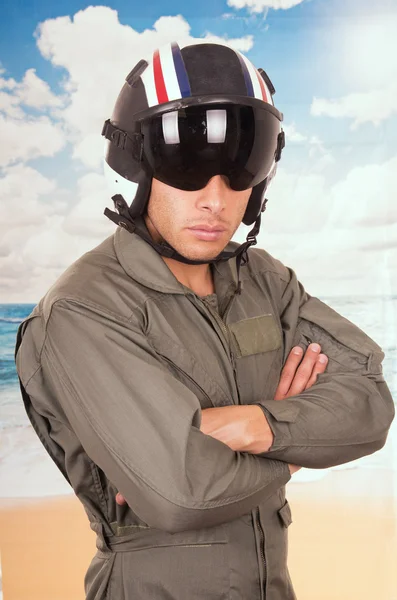 Ung snygg pilot bär uniform och hjälm över stranden bakgrund — Stockfoto