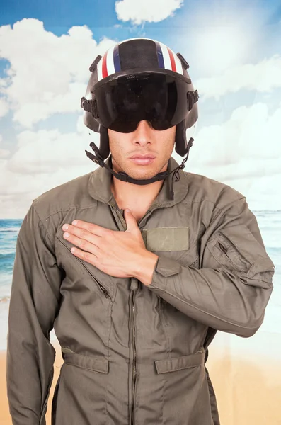 Junge hübsche Pilot trägt Uniform und Helm über Strand Hintergrund — Stockfoto