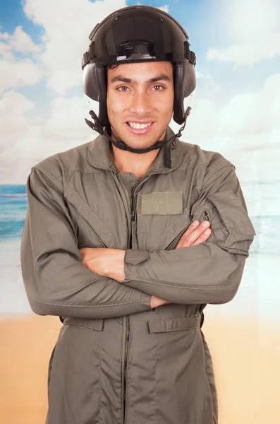 Mladý pohledný pilot nosit uniformu a helmu beach pozadí — Stock fotografie