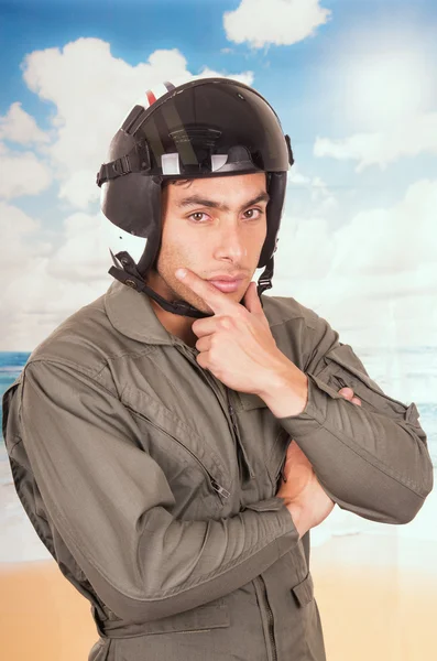 Joven piloto guapo vistiendo uniforme y casco sobre fondo de playa — Foto de Stock