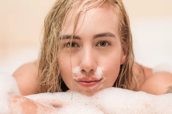 Primer plano de hermosa rubia joven teniendo un baño de burbujas — Foto de Stock