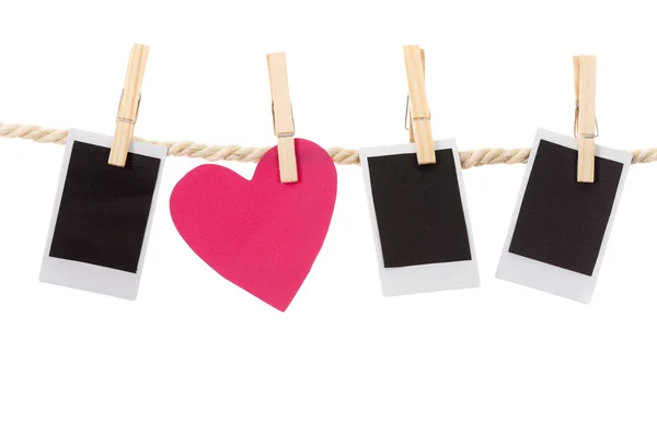 Instant photographs and heart shape hanging on a rope clothesline — Stock Photo, Image