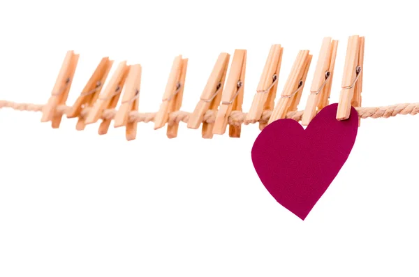 Pink heart shape and clothespins hanging on a rope clothesline — Stock Photo, Image