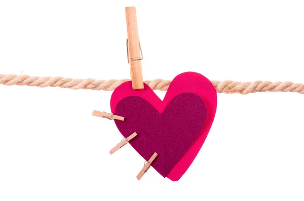 Pink heart with small clothespins attached hanging on a rope clothesline — Stock Photo, Image