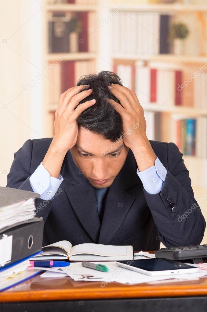 young stressed overwhelmed man with piles of folders on his desk
