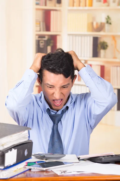 Gestresster junger Mann mit Aktenstapeln auf seinem Schreibtisch überwältigt — Stockfoto