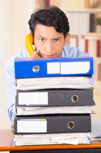 Gestresster junger Mann mit Aktenstapeln auf seinem Schreibtisch überwältigt — Stockfoto