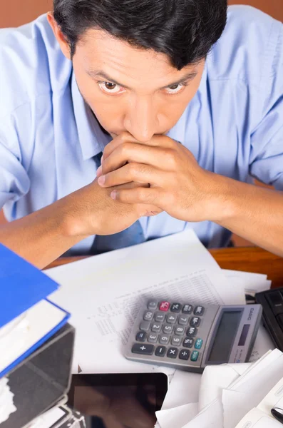 Gestresster junger Mann mit Aktenstapeln auf seinem Schreibtisch überwältigt — Stockfoto